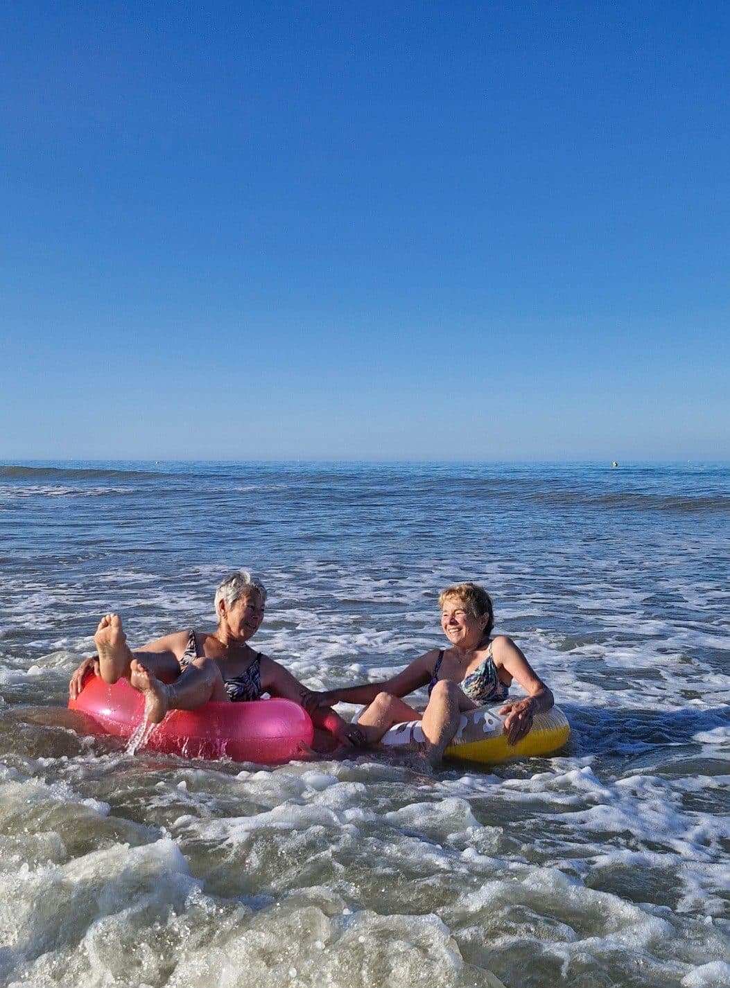 Deux baigneuses sur des bouées dans les petites vagues